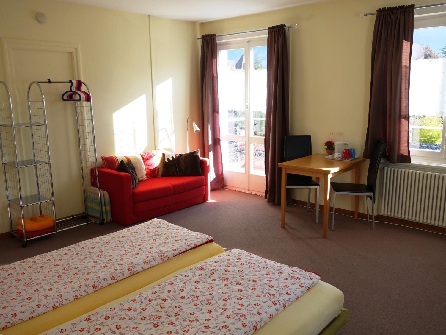 Superior Twin Room: twin beds, red sofa and balcony door